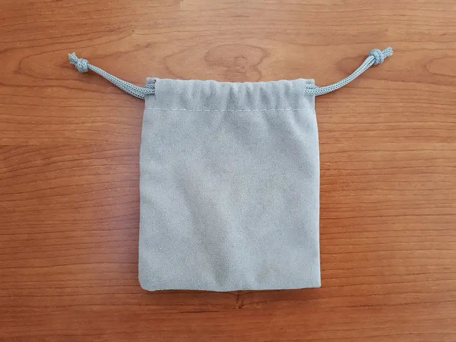 A small soft grey drawstring pouch lying flat on a timber bench